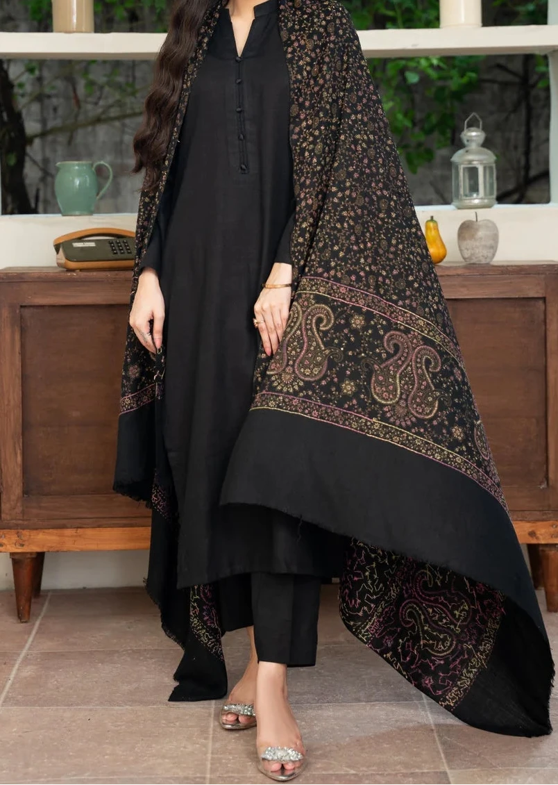 Woman wearing a black outfit with a patterned shawl in an indoor setting.