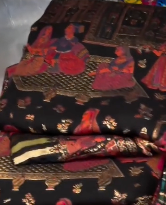 Stack of patterned fabric with people sitting on a bench