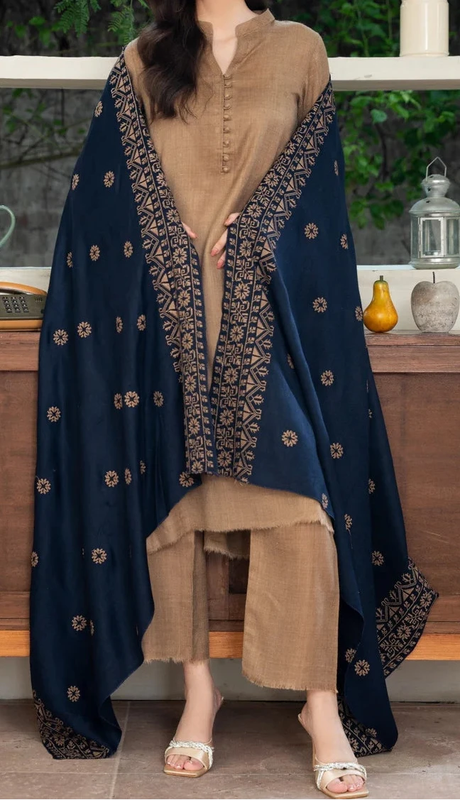 Woman wearing a navy blue and gold traditional outfit in front of a wooden cabinet.
