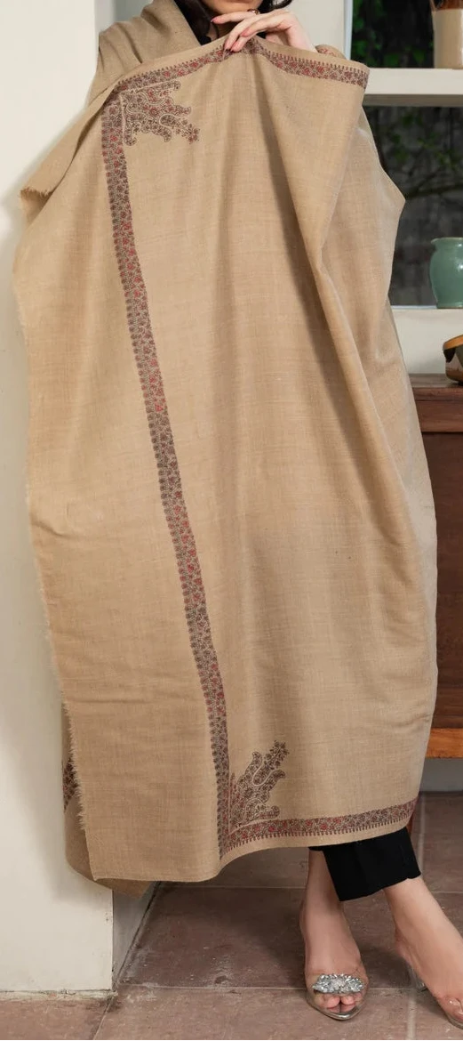 Woman wearing a beige embroidered scarf in a kitchen setting
