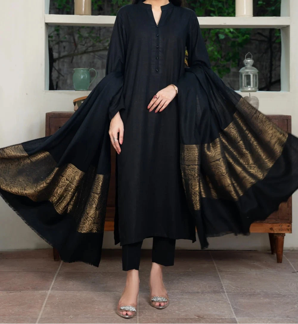 Woman wearing a black outfit with gold details in a room setting