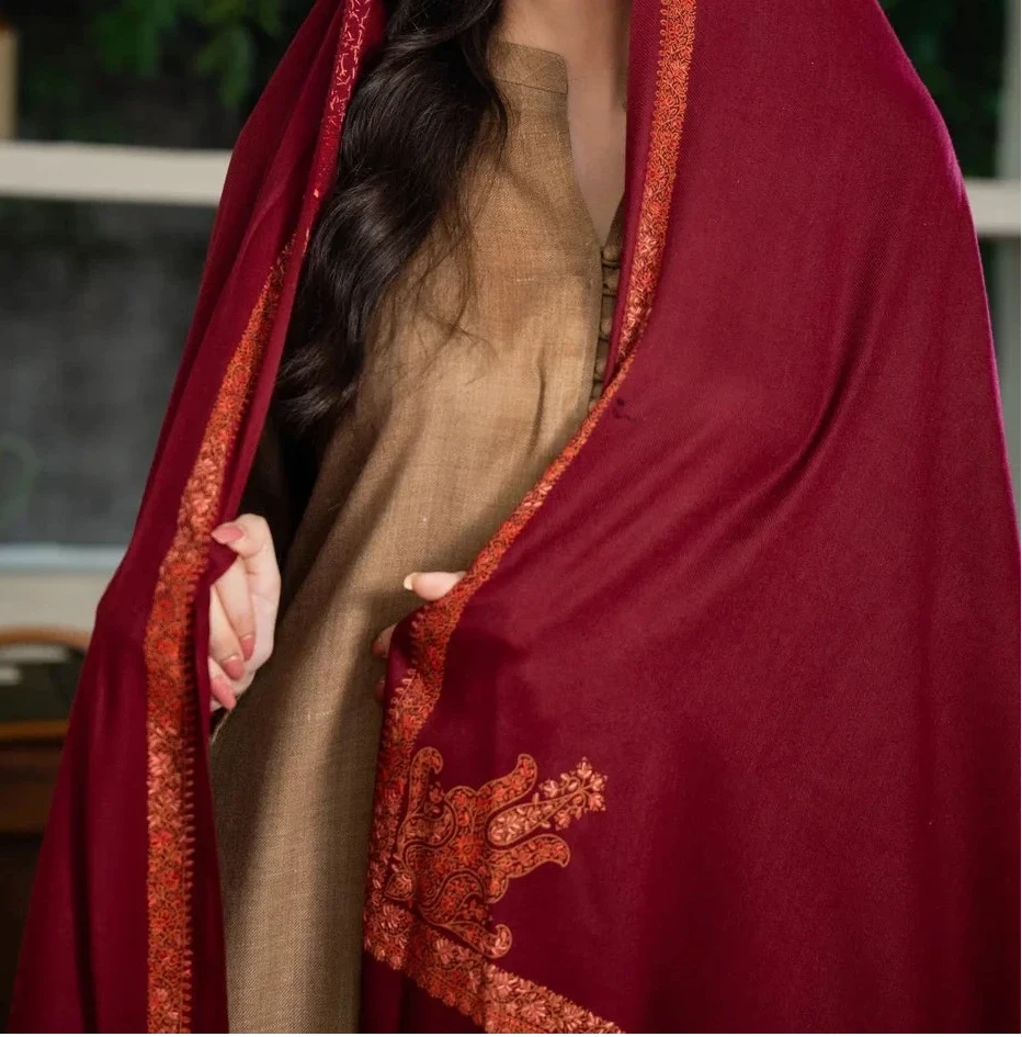 Woman wearing a red dupatta with gold embroidery in an indoor setting