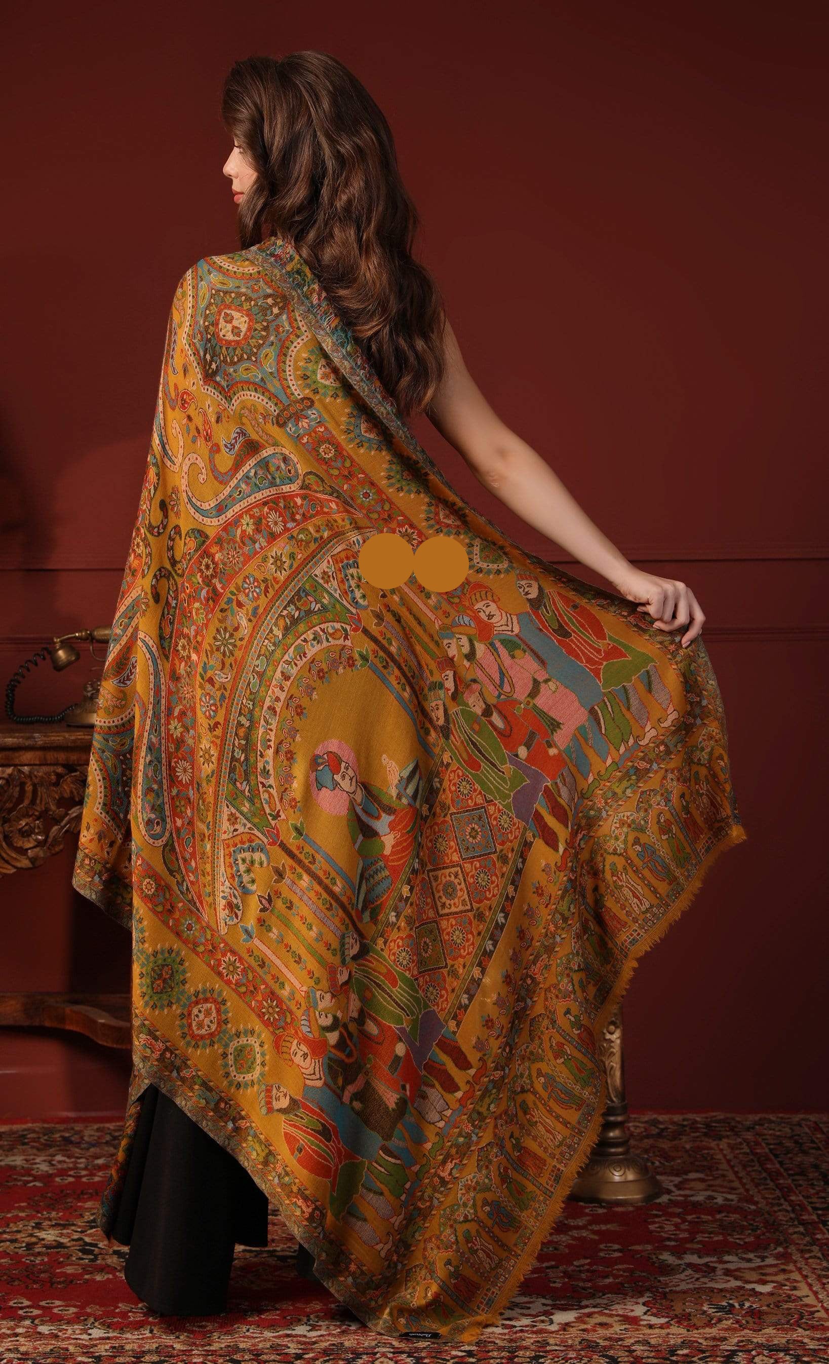 Woman wearing a colorful patterned shawl against a red wall.